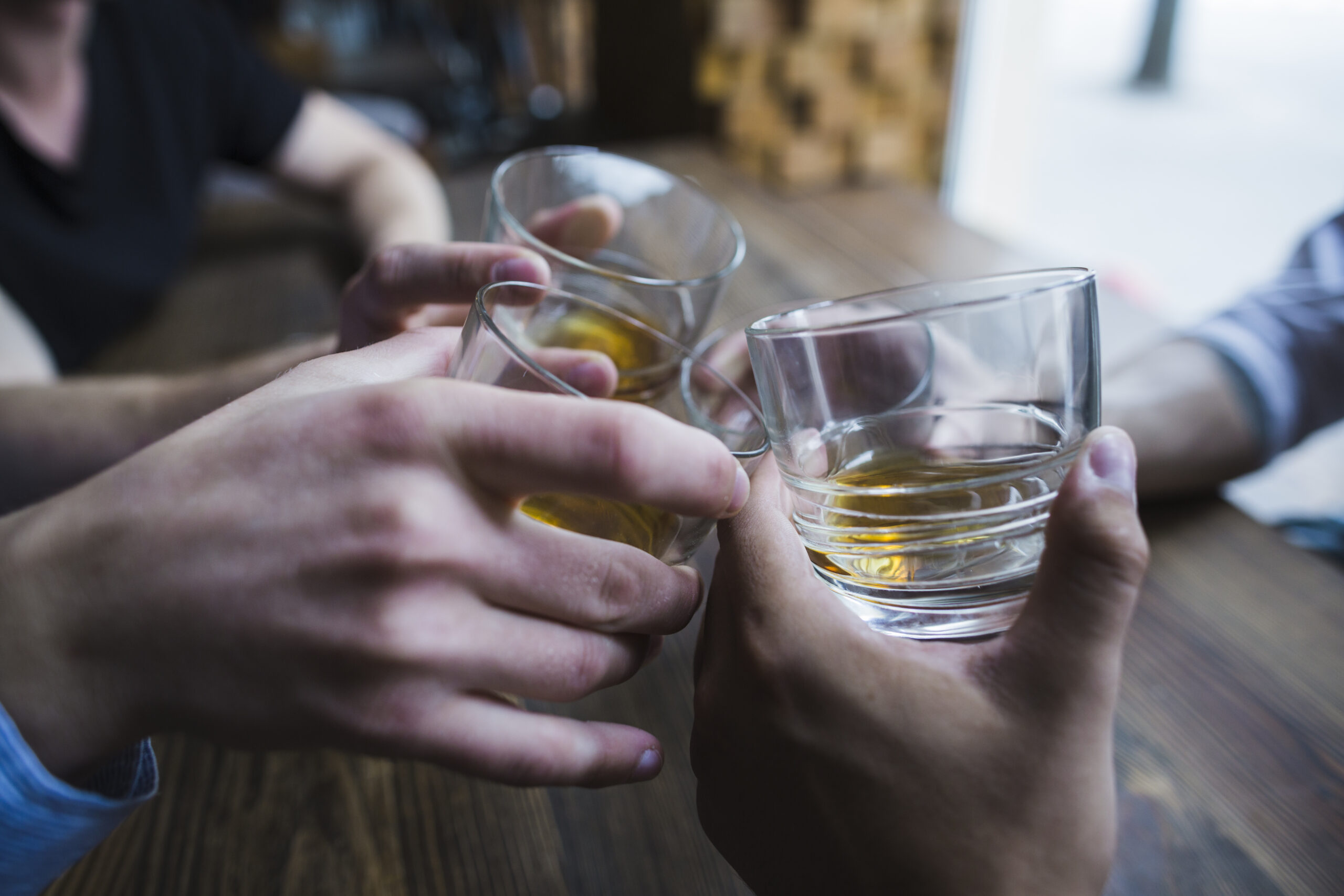 close-up-hands-toasting-whisky-glasses
